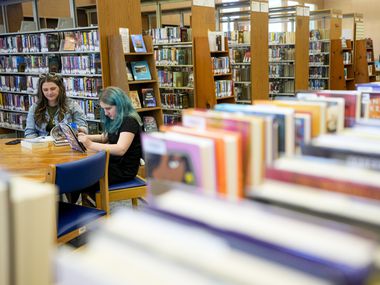 Mother and daughter read in a library, Thursday, May 18, 2023.
