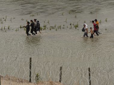 Migrants walked along concertina wire by the Rio Grande in Eagle Pass on July 12. A state...