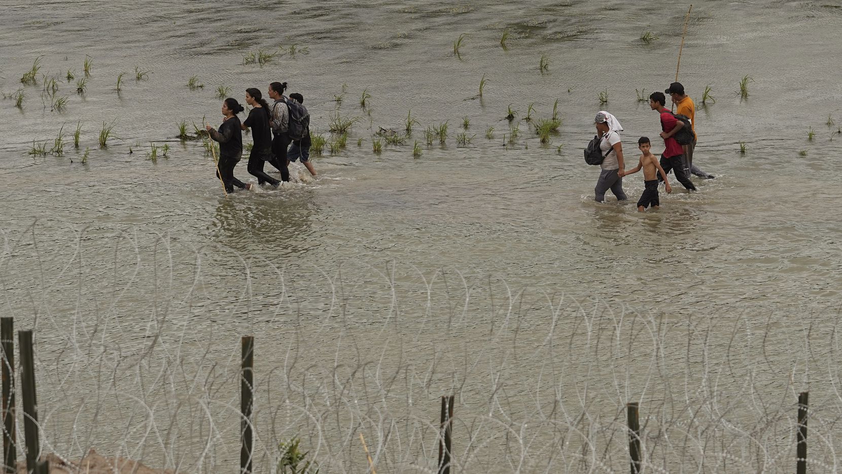 Migrants walked along concertina wire by the Rio Grande in Eagle Pass on July 12. A state...